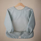 mushie Long Sleeve Baby Bib | Mess Free & Waterproof Fabric for Toddlers | Adjustable Fit for Ages 6-24 Months (Roman Green)