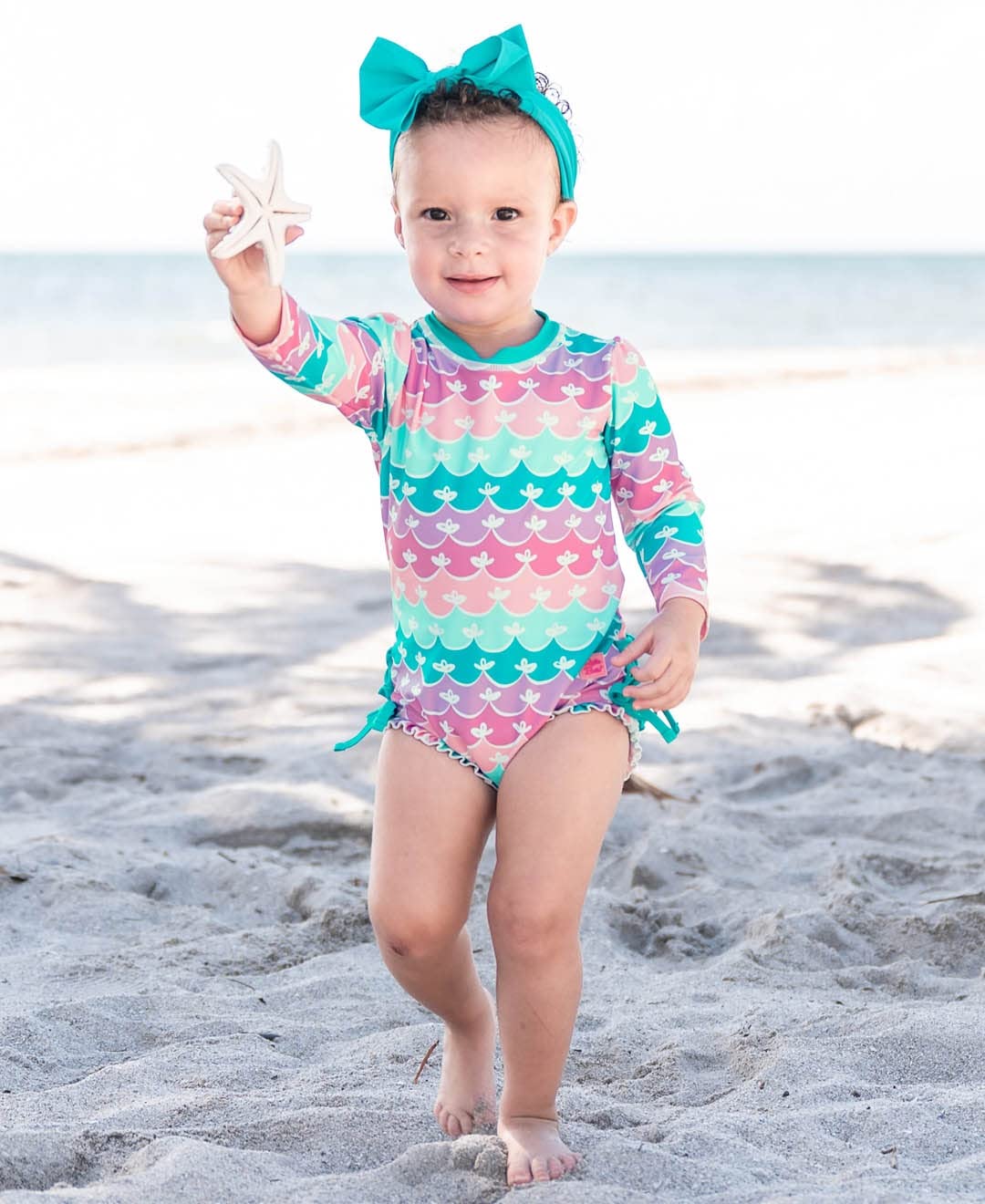 RuffleButts Baby Girls UPF 50+ Sun Protection Novelty Print Long Sleeve One Piece Rash Guard Swimsuit with Zipper - Mermaid/Aqua